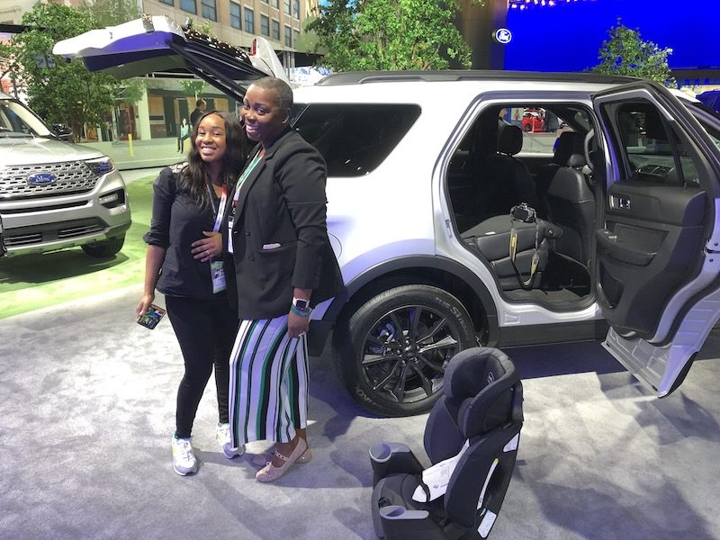 Which 2 Row SUVs Are Best For Child Car Seats? The Ultimate Car Seat Challenge 4 Two Woman Posing Next To A Suv Next To A Child Car Seat